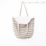 A front view image of the shoulder Bag, Jute / Chloe Natural Black Stripe by Will & Atlas hanging on a hook showing the inside lining of the bag