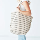 A side view of a model carrying the Shoulder Bag, Jute / Chloe Natural Black Stripe by Will & Atlas