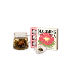 image of open box of the qi inner awakening blooming tea next to a tea pot