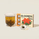 image of open box of the qi inner  radiance blooming tea next to a tea pot