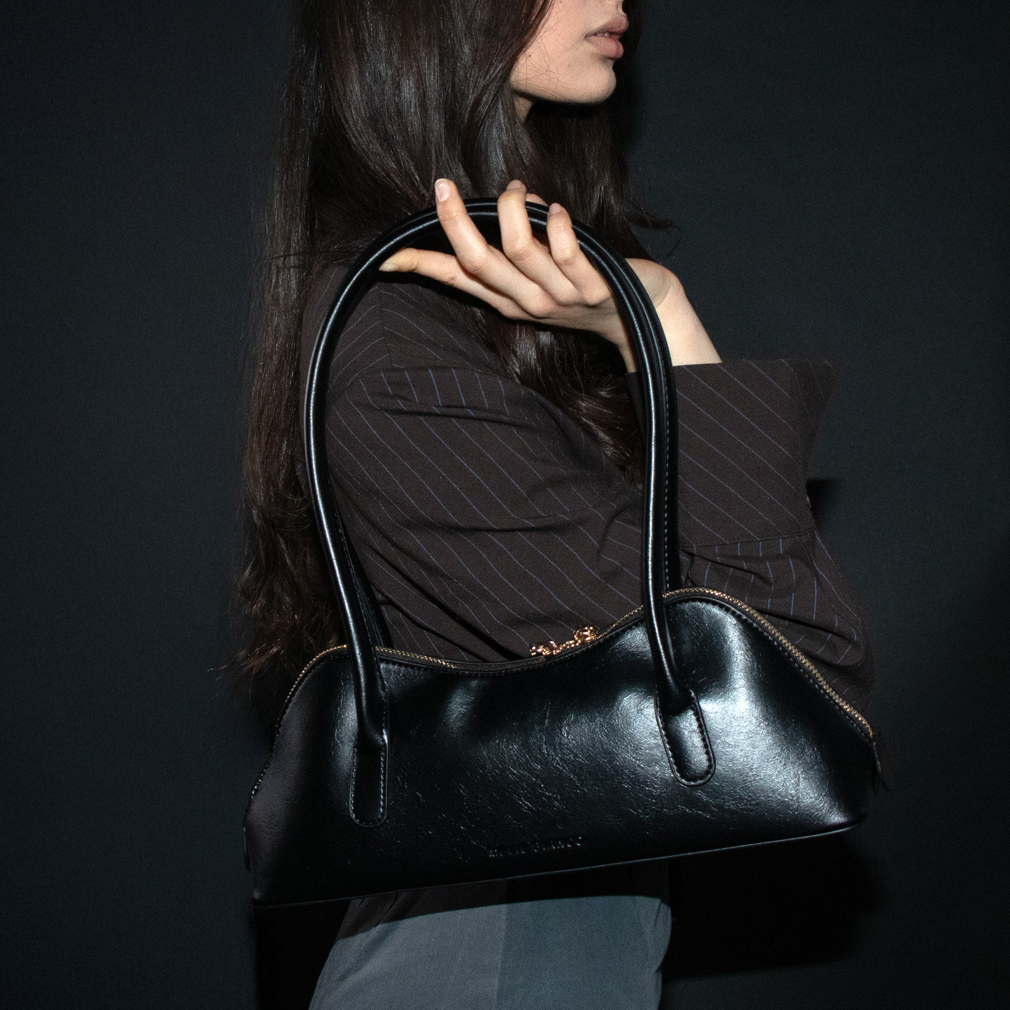 Side view of model holding the black Dakota shoulder bag by Melie Bianco
