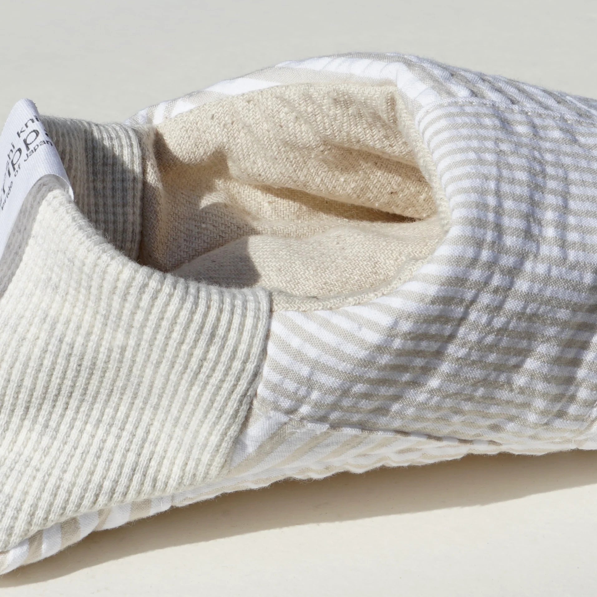 Close up of beige and white striped slippers  on a white background