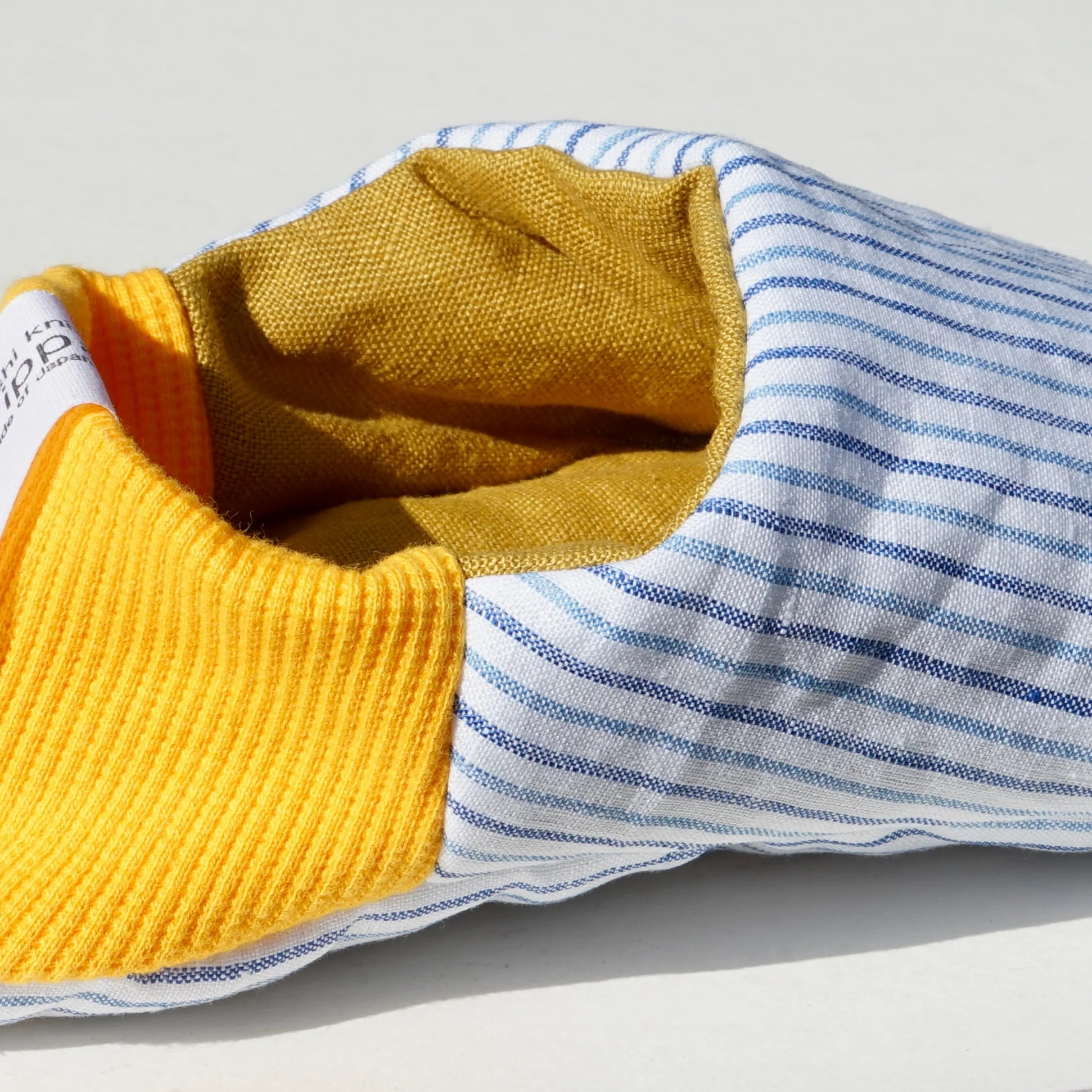 Close up of blue striped slippers with yellow heels on a white background