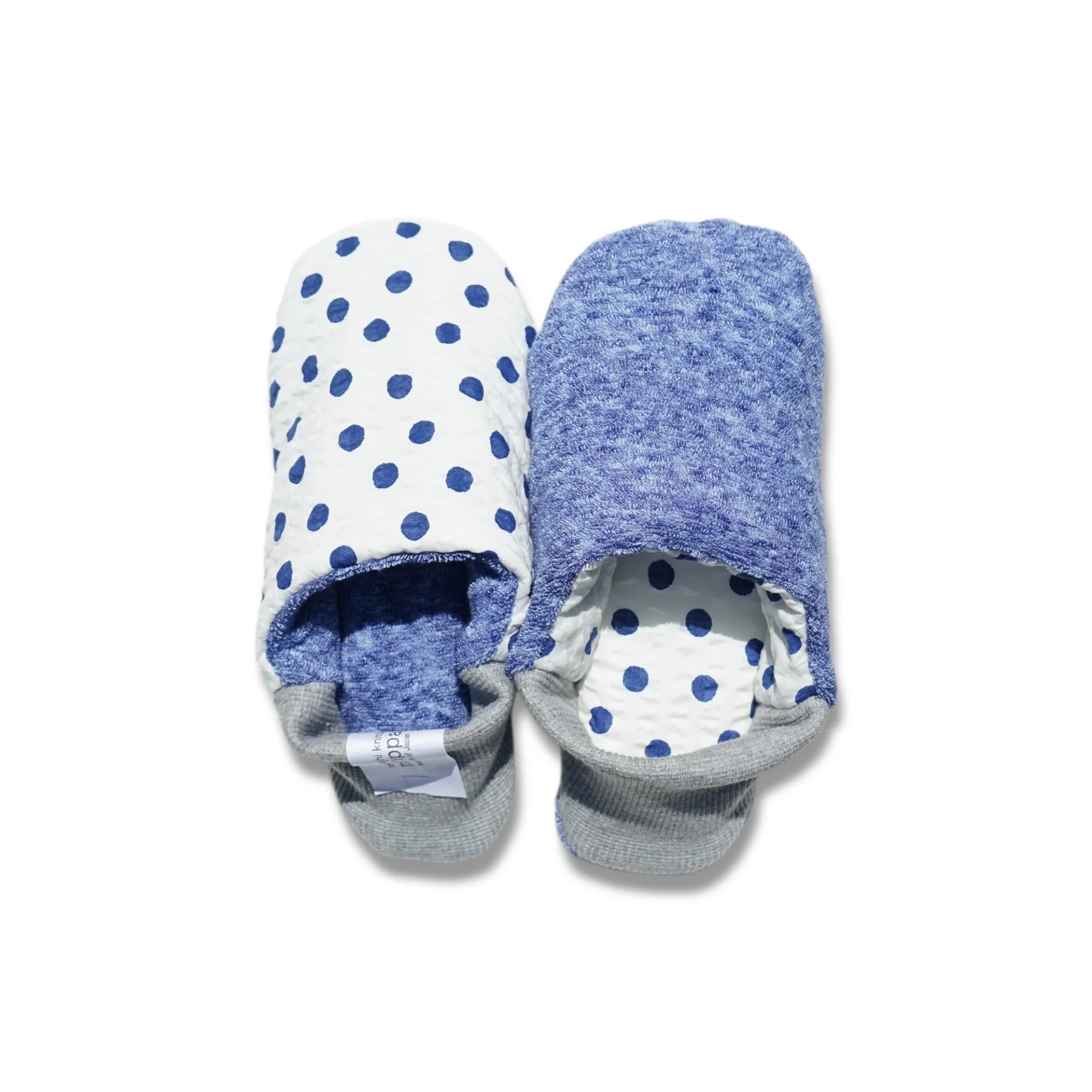 Pair of blue and white polka dot slippers with blue interior and gray heels on a white background