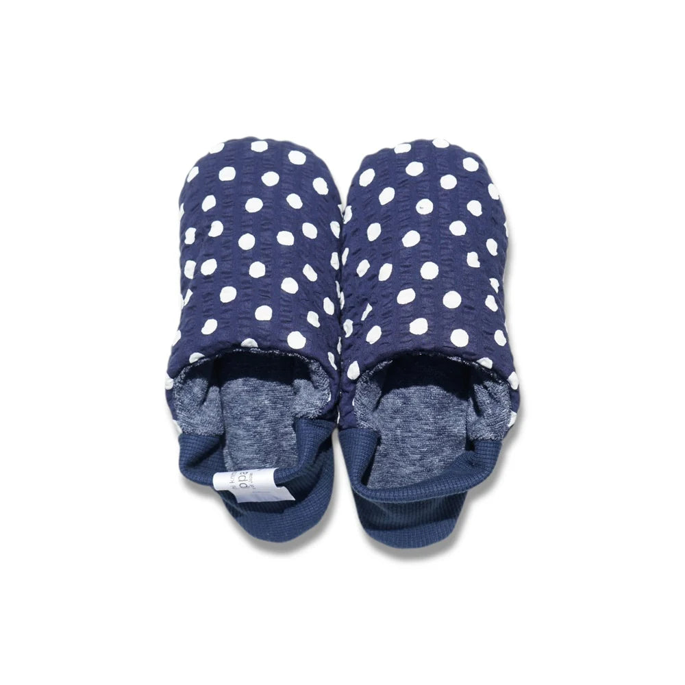 Pair of navy blue and white polka dot slippers with blue interior and blue heels on a white background